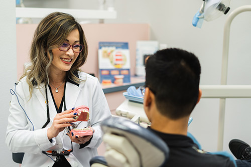 Smiling Dr. Lee discussing oral hygiene with a patient at Irvine Dentistry